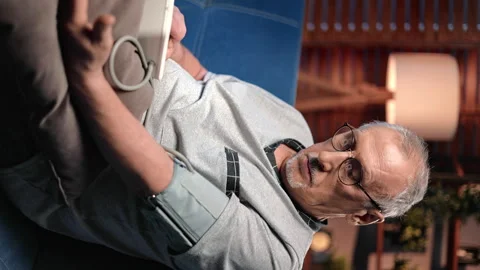 VERTICAL VIDEO POV Elderly man taking blood pressure by modern medical equipment 動画素材 265793315