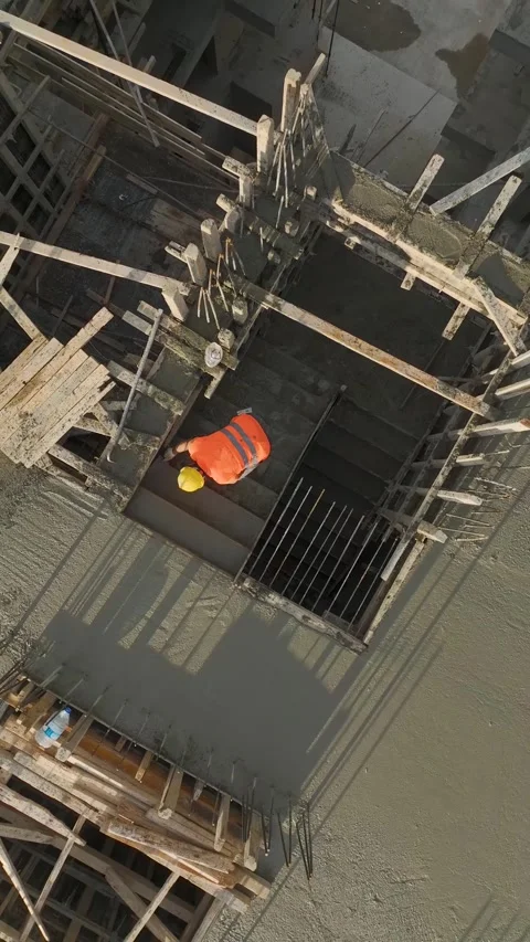 Vertical Video: Precision concrete work as a worker levels freshly poured Stock Footage 297655010