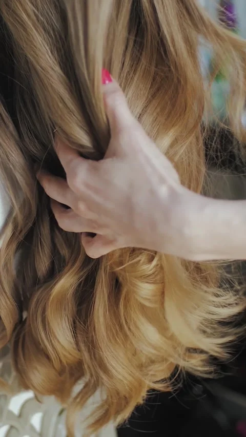 Vertical video. The process of creating stylish hair with glamorous waves for a Stock Footage 311449272