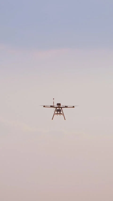Vertical video. Professional agricultural multi-rotor drone flying in the sky 動画素材 333860059