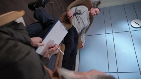 Vertical video. Professional gray-haired male psychologist listens to a patient Stock Footage 148853581