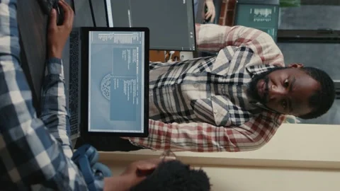 Vertical video Programer sitting at desk with multiple screens running code Stock Footage 194146568