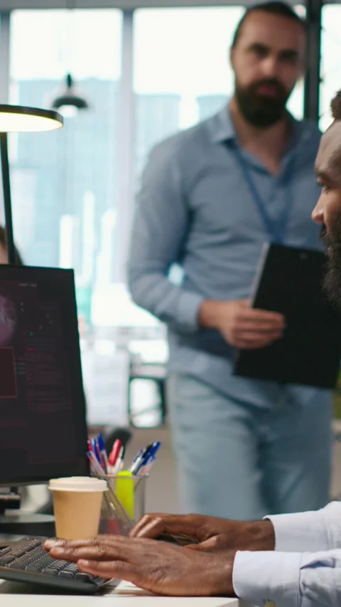 Vertical video Programmer in office requesting help from coworkers to fix 動画素材 312769599