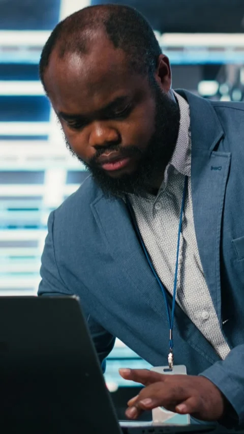 Vertical video Programmer at server farm workplace desk using laptop, doing Stock Footage 330027928