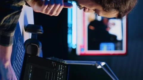 Vertical video Programmer writes code on laptop screen while in apartment office Stock Footage 264124068