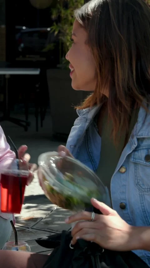 Vertical video: Pulling bowl from bag, woman in denim opening, passing salad at Stock Footage 348636220