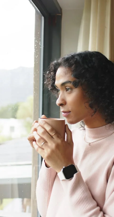Vertical video: Rain tapping window, non-binary African American gripping mug Stock Footage 345129014