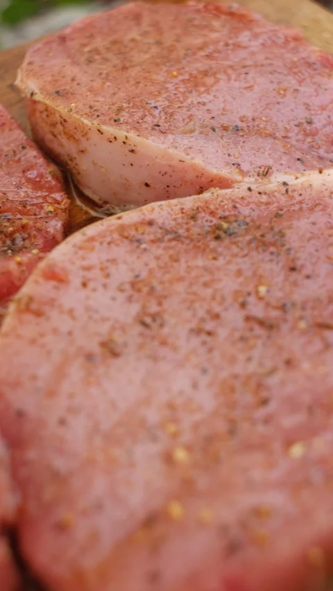 Vertical video of raw fresh pork meat cut into slices for frying on wooden board Stock Footage 297946212