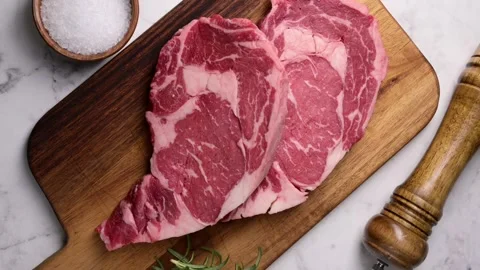 Vertical video, raw ribeye steak beef on white marble background Stock Footage 260963728