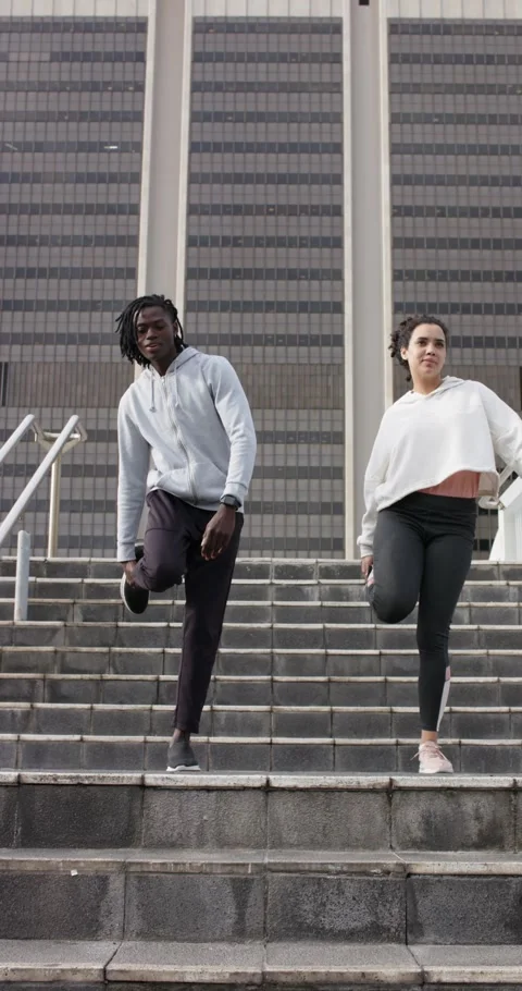 Vertical video: Reaching top step of stairs, Diverse couple lifting knees Stock Footage 345491504