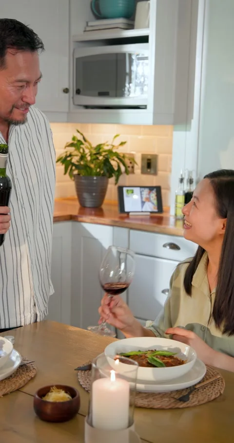Vertical video: Reaching for wine bottle, Asian couple pouring wine and toasting Stock Footage 346721094