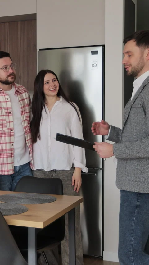 Vertical video Real estate agent man shows modern house to a young couple. Stock Footage 340082429