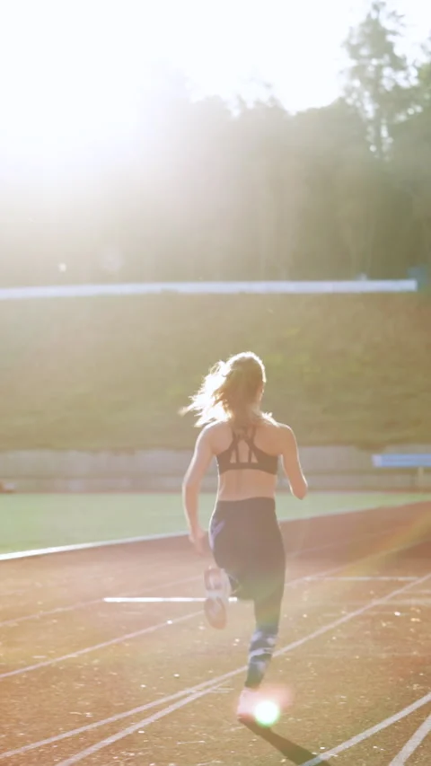 Vertical Video of Rear view of athletic woman running on track stadium at summer Stock Footage 304827074