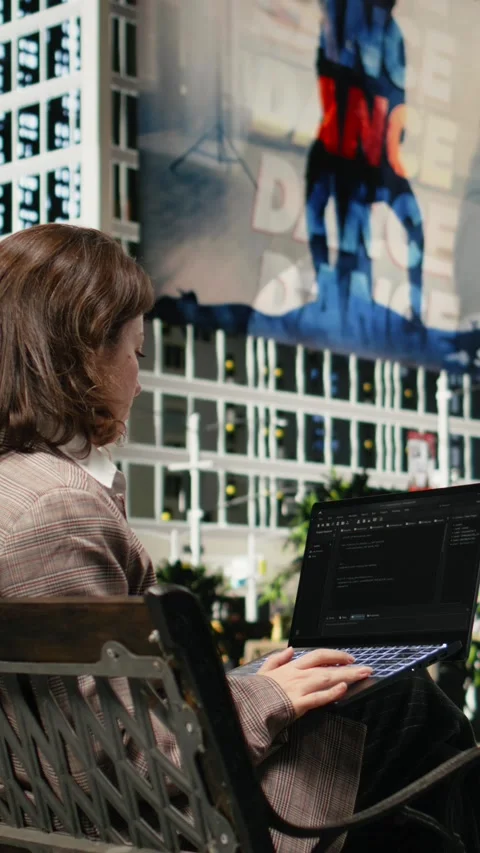 Vertical video Rear view of female programmer on park bench writing code on Video stock 343559146