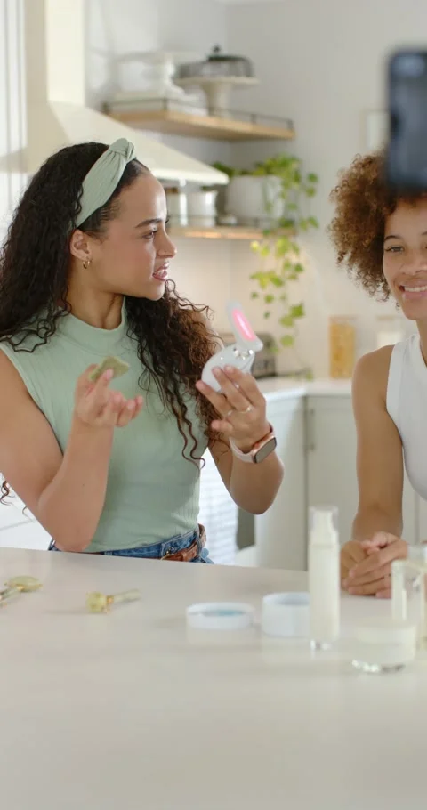 Vertical video: Recording, left host in mint top demoing skincare device in Stock Footage 346600156