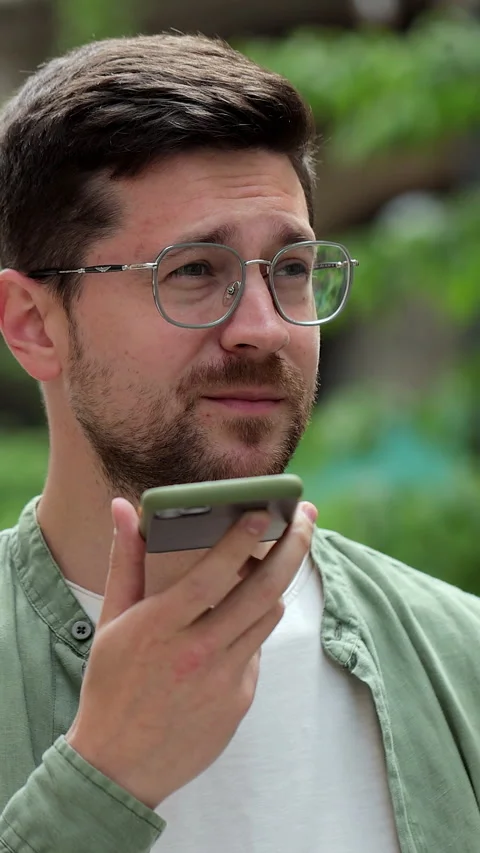 Vertical video. Recording Voice Message on Mobile Phone: Young Man in Glasses. Stock Footage 345240810