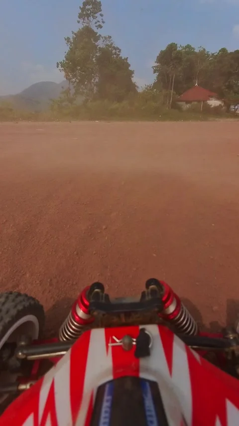 Vertical Video of Red and white RC car grips dusty terrain. Stock Footage 340051827