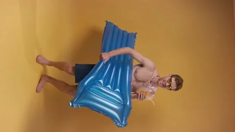 Vertical video Red-haired man dancing in beach shorts with an inflatable Stock Footage 202069900