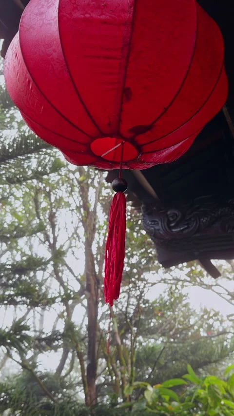 Vertical video. Red Lantern Hanging Under Ornate Wooden Roof With Foggy Forest B Stock Footage 323665900