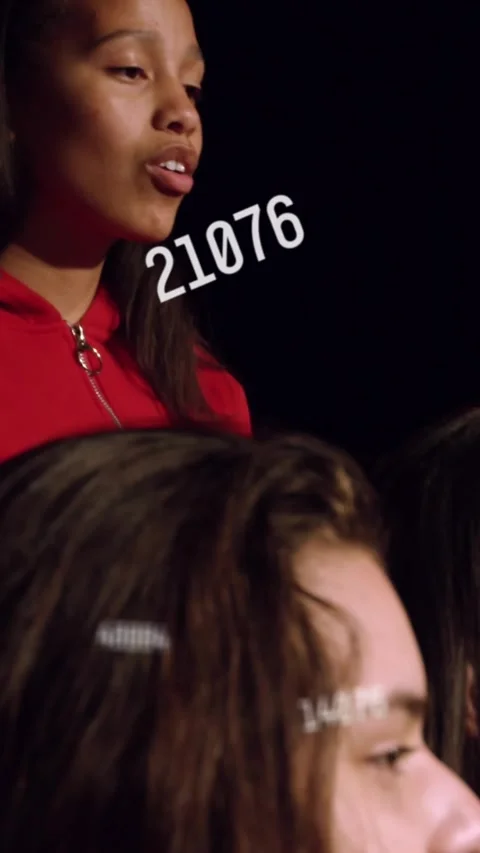 Vertical video: Red lead singing as numbers drifting over faces, camera pulling Stock Footage 331238079