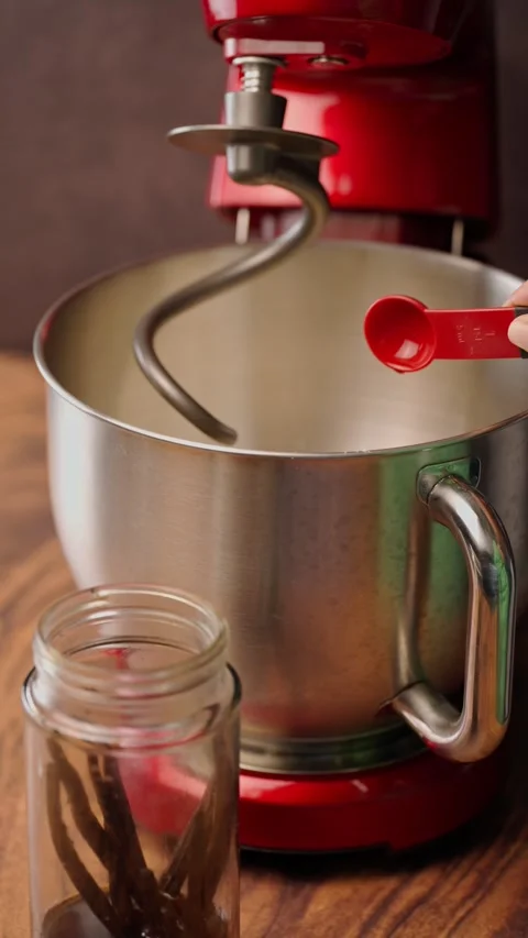 Vertical video, Red stand mixer, adding a teaspoon of natural vanilla essence Stock Footage 282499719