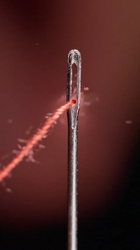 Vertical video. Red Thread Passes Through a Sewing Needle Eye, Extreme Macro Vie Stockbeeldmateriaal 341416925