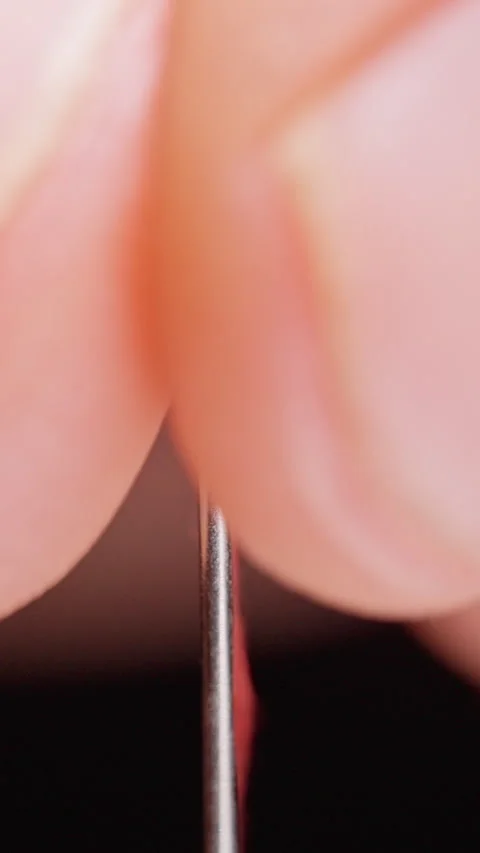 Vertical video. Red Thread Passes Through a Sewing Needle Eye on a Black Backgro Stockbeeldmateriaal 341416957