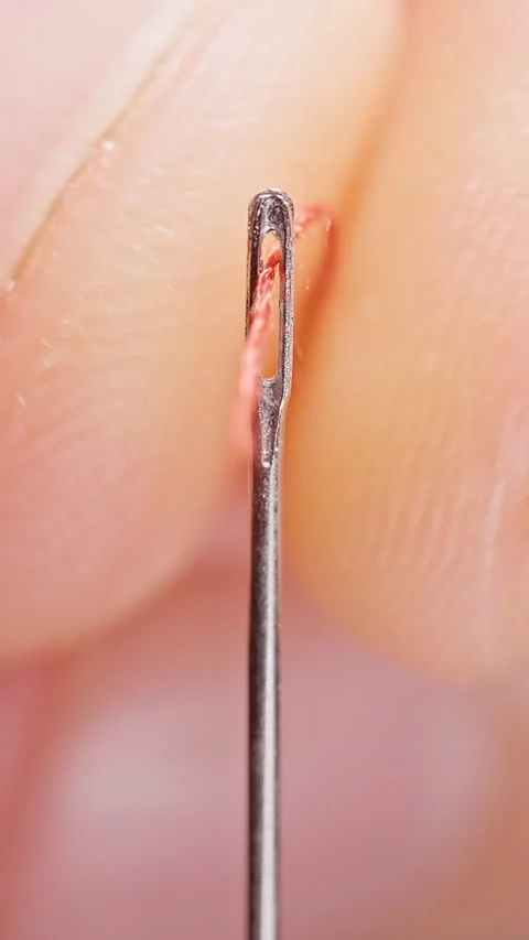 Vertical video. Red Thread Passes Through a Sewing Needle Eye, Extreme Macro Vie Stockbeeldmateriaal 341417363