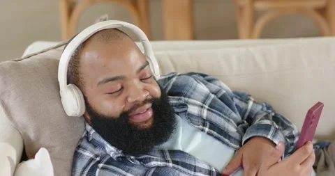 Vertical video: Relaxing man in plaid opening eyes, scrolling phone with Stock Footage 335514873