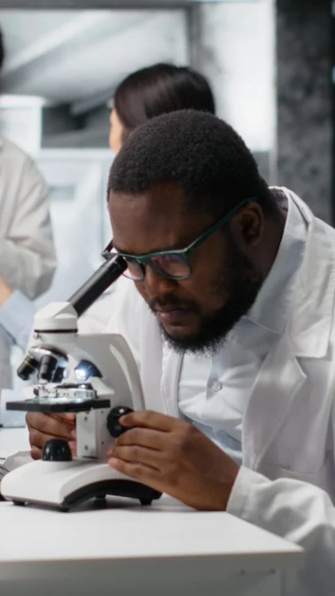Vertical video Researcher operating microscope, doing observations in laboratory Stock Footage 319507097