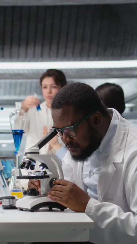 Vertical video Researcher operating microscope, doing observations in laboratory Stock Footage 319507143