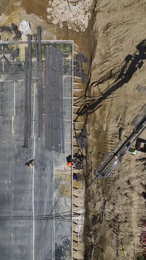 Vertical Video: Residential complex foundation being prepared as workers bend Stock Footage 297663585