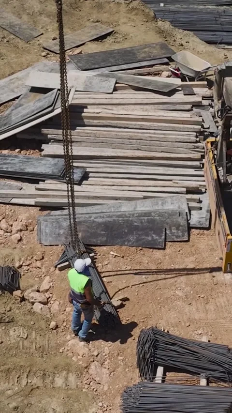 Vertical Video: Residential complex foundation prep with workers bending rebar Stock Footage 297664487