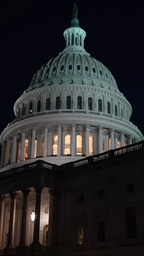 Vertical video to right showing the US Capitol with lights and flags waving in Stock Footage 314658787
