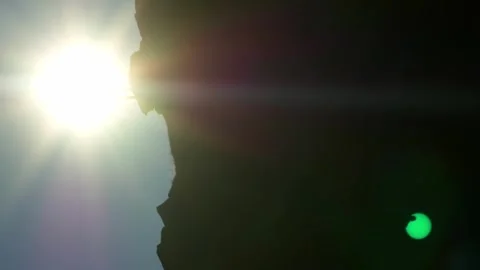 Vertical video. A rock on which stands the silhouette of a man with the sun Stock-Footage 256231516