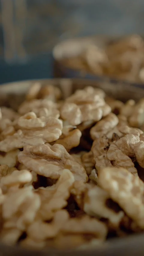 Vertical video Rustic bowls filled with fresh walnut kernels in a warm kitchen Stock Footage 329617461