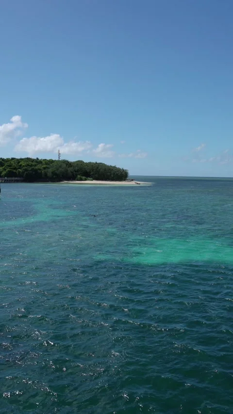 Vertical video of Sailing past a tropical island with a pier in turquoise water Stock-Footage 330942161