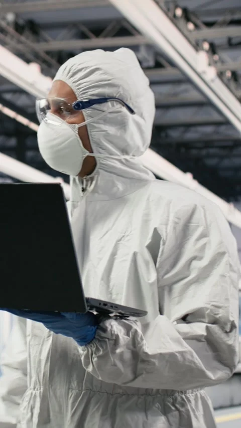 Vertical video Scientist in microchip factory cleanroom uses laptop Stock Footage 333615215