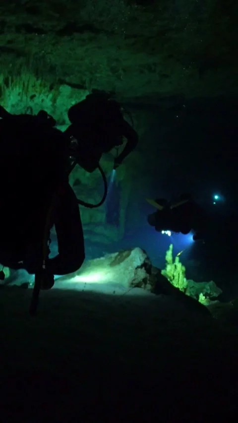 Vertical video of Scuba divers with flashlights exploring underwater cave cenote Stock Footage 330467873