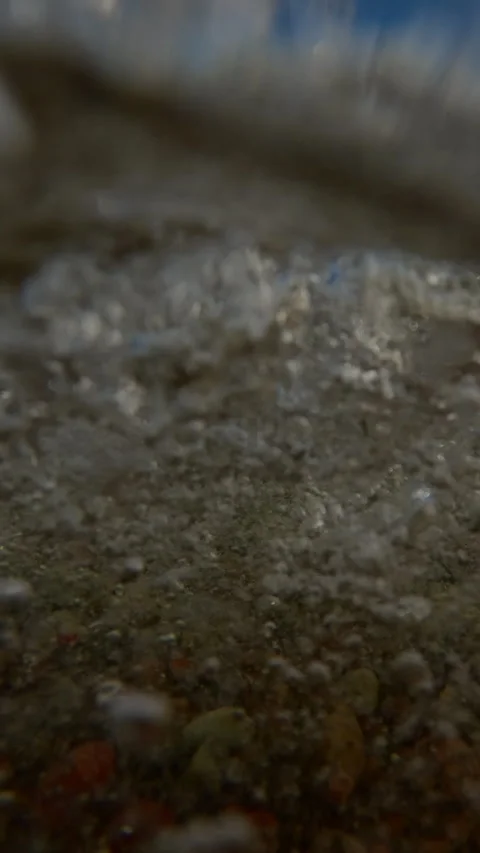 Vertical video, Sea waves break on pebble shore throwing stones at lens, moving 스톡 동영상 330177079