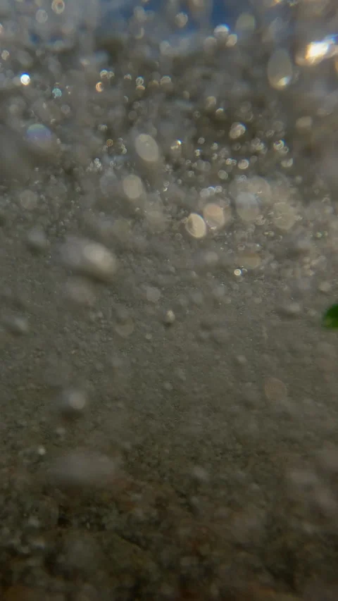 Vertical video, Sea waves crush the pebble rocks of the beach, Underwater split Vidéo 340456928