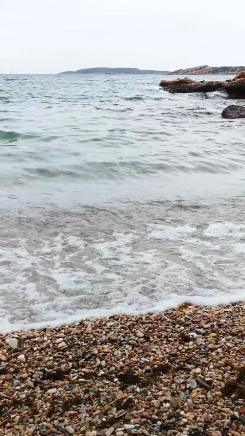 Vertical video of sea waves gently washing over colorful pebbles on the beach Stock Footage 312778907