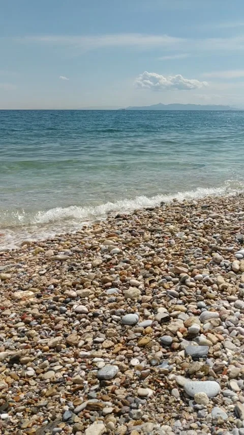 Vertical video of sea waves gently washing over colorful pebbles on the beach Stock Footage 312838958