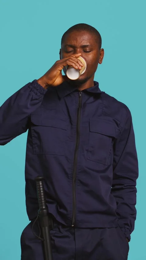 Vertical video Security agent uses coffee cup to remain energized while securing Stock Footage 277425657