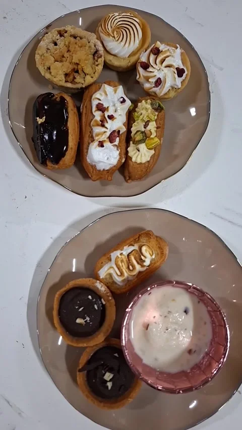 Vertical Video of a Selection of Eclairs Arranged on Plates, Viewed from Above. Stock Footage 334893599