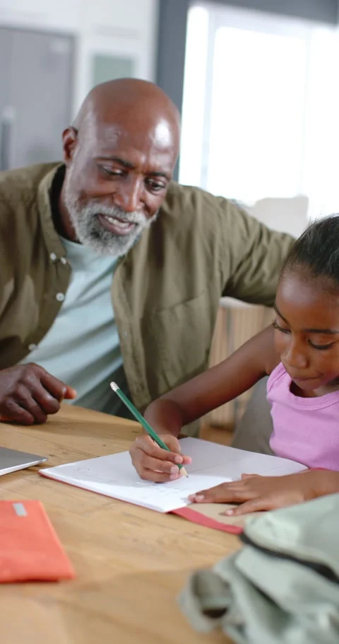 Vertical video: Senior African man making OK, guiding child writing notebook Stock Footage 345218683