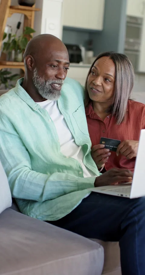 Vertical video: Senior couple using laptop on sofa after checkout holding card Stock Footage 345492046