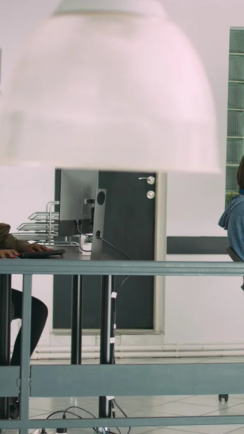 Vertical video: Senior developers coding on laptop in software agency office Stock Footage 218576343