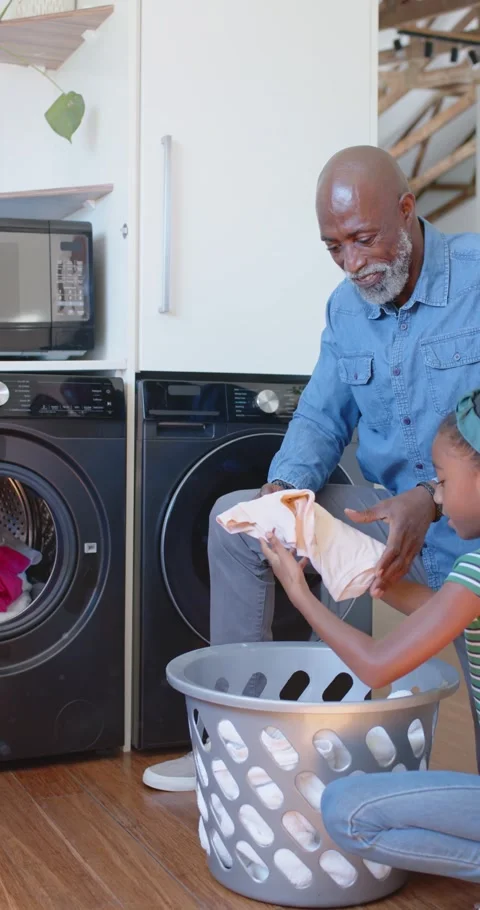 Vertical video: Senior man sorting while child handing clothes from bin into Stock Footage 345396757