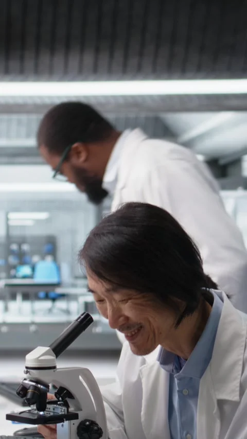 Vertical video Senior microbiologist in lab using scientific microscope to Stock Footage 319505310